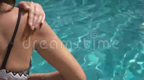 一个女人在游泳池里涂抹太阳霜的视频视频的预览图