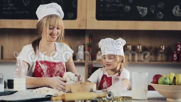 妈妈和女儿穿着同样的衣服在舒适的厨房里准备面团玩得很开心他们准备圣诞饼干视频的预览图