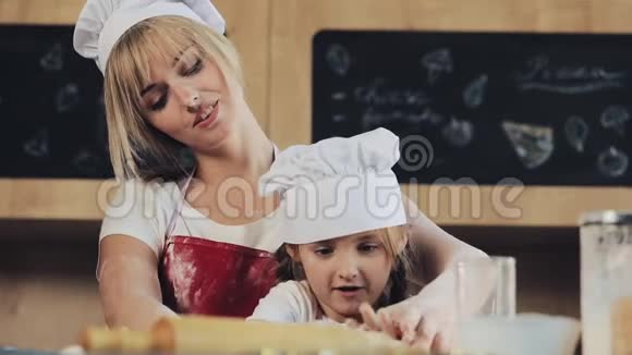 妈妈和女儿穿着同样的衣服在舒适的厨房里准备面团玩得很开心他们准备圣诞饼干视频的预览图