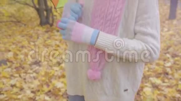 秋天公园里可爱的少女带着彩色雨伞微笑视频的预览图