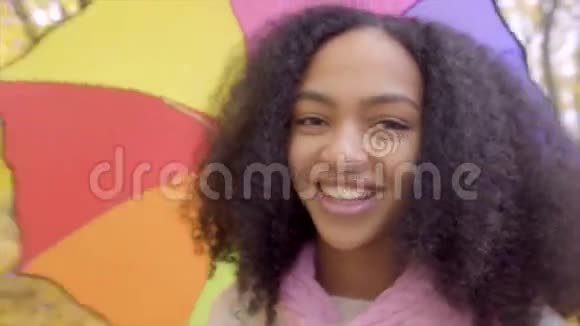 秋天公园里可爱的少女带着彩色雨伞微笑视频的预览图