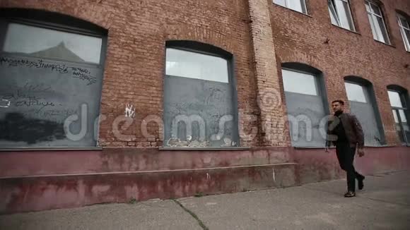 成功的幸福人站在老厂的砖墙旁视频的预览图