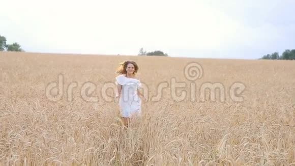 穿着白色连衣裙在田野上奔跑的年轻女子视频的预览图