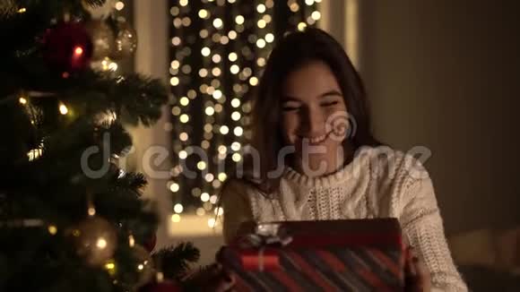 女人在圣诞树下打开新年礼物视频的预览图