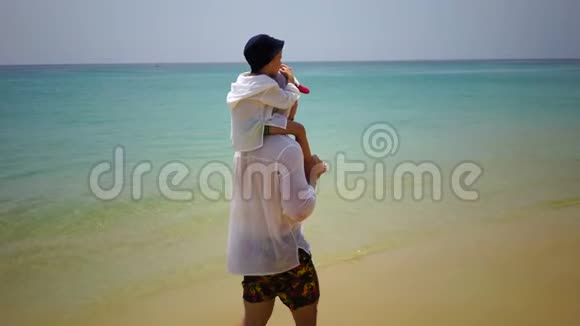 父子俩步行沿着靠近海洋的海滩散步视频的预览图