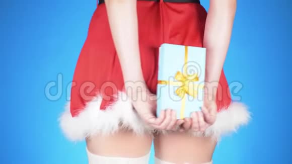 圣诞节假期年轻迷人的女人穿着雪少女的服装带着礼物在蓝色的背景上跳舞特写视频的预览图