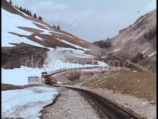 火车穿过山脉行驶在铁轨上视频的预览图