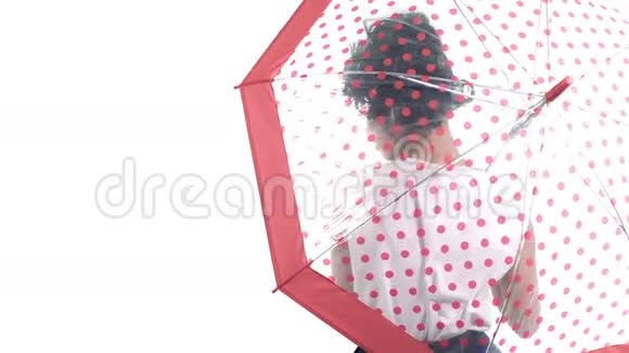 亚洲女人带着一把带有圆点图案的雨伞看着白色背景上的相机视频的预览图