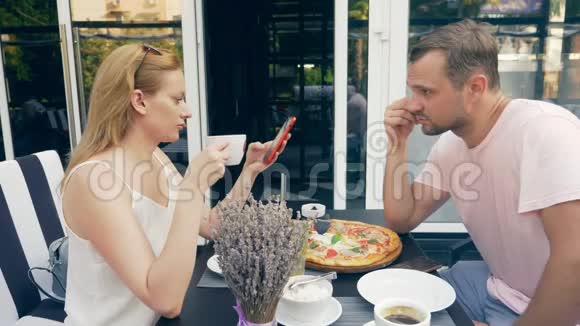 一对在户外咖啡馆男女约会一个搭档看着他的手机第二个试图和他说话4k视频的预览图
