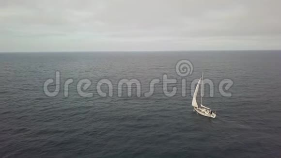 白帆游艇航行在蓝色的海洋和多云的天空景观无人机视野视频的预览图