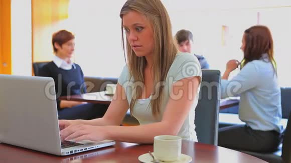 微笑的女人在食堂的笔记本上打字视频的预览图