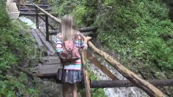 山上桥上的孩子大自然中的孩子徒步旅行看着河流的女孩小溪视频的预览图