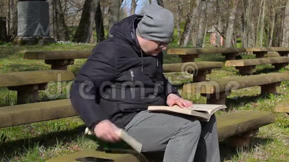 在公园的长凳上读两本书的人视频的预览图