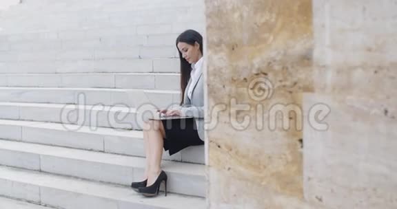 微笑的女人在楼梯上用笔记本电脑视频的预览图