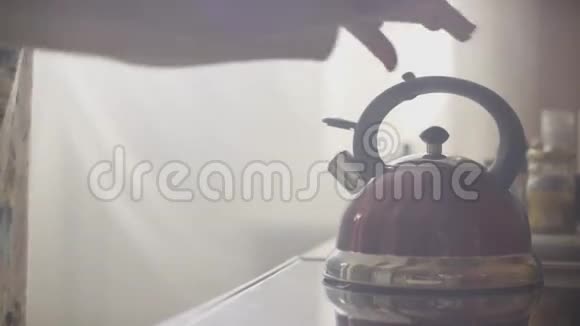 女孩把蓝色的水壶放在厨房的煤气炉上手里拿着吹口哨的水壶视频的预览图