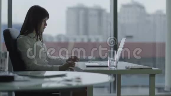 在现代办公室里用笔记本电脑工作的年轻女商人她专注而认真视频的预览图