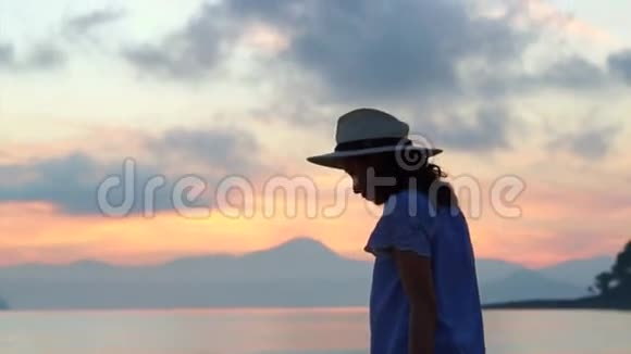 亚洲妇女剪影与帽子享受海景在日出美丽的热带海滩和景观视频的预览图