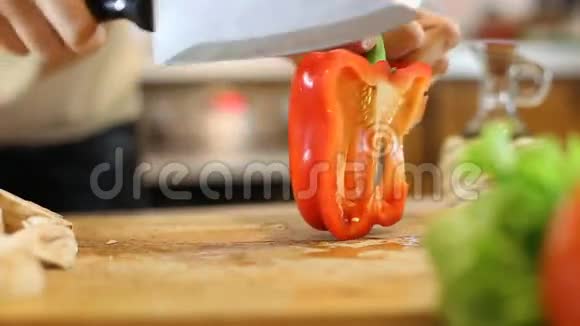 女人用手在木切割板上切甜的红铃椒视频的预览图