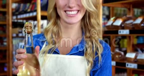 在超市拿着橄榄油瓶的女员工微笑视频的预览图