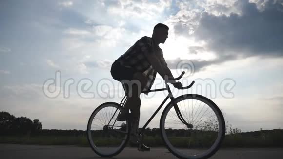 男子骑老式自行车的剪影背景是美丽的日落天空在乡村骑自行车的运动型男子视频的预览图