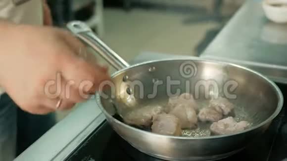 厨师在餐厅厨房里用煎锅煎肉视频的预览图