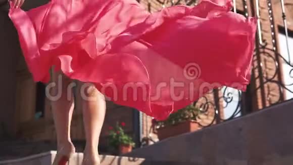 穿着红色裙子的女孩在夕阳下走在街上慢动作视频的预览图