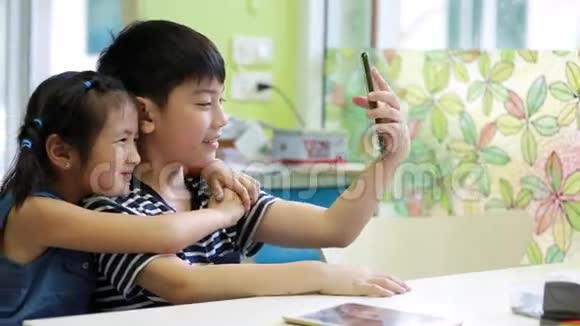 亚洲小男孩和小女孩用手机拍照视频的预览图