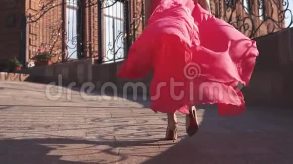 穿着红色裙子的女孩在夕阳下走在街上慢动作视频的预览图
