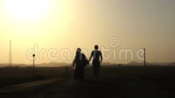 日落时分埃及夫妇手牵着手走在路上视频的预览图
