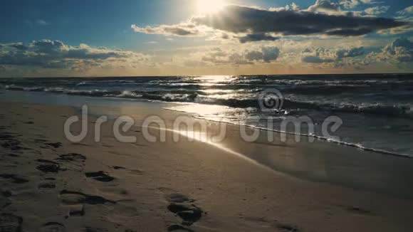 在海浪和沙滩上的云层后面日落视频的预览图