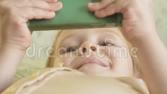 幸福的女孩金发和辫子躺在沙发上用电话微笑肖像视频的预览图