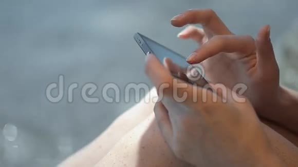沙滩上使用智能手机的女士双手视频的预览图