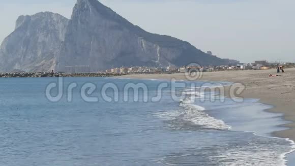 地中海在美丽的海浪中在白沙和直布罗陀岩石的背景下拍打着视频的预览图