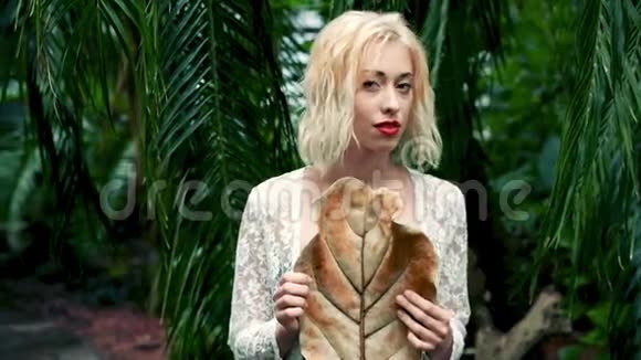 热带植物园金发女子的温柔肖像视频的预览图
