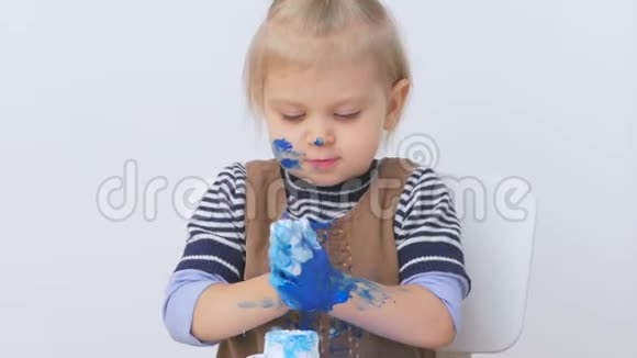 一个小女孩在画画时把她的手和衣服弄脏了幼儿仔细检查脏手视频的预览图