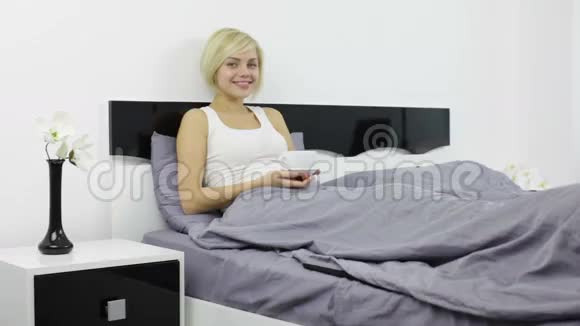 躺在床上喝咖啡的女人开心的微笑视频的预览图