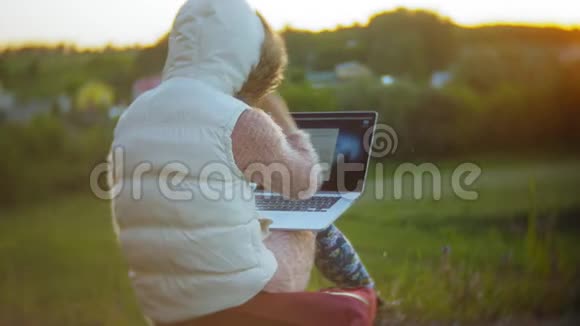 年轻女子在老式铁路桥附近的笔记本电脑上工作视频的预览图