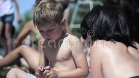 小男孩和妈妈在海滩上玩智能手机视频的预览图