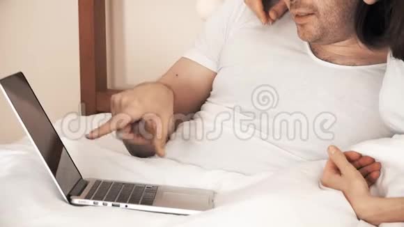一对夫妇在家里的床上用笔记本电脑视频的预览图