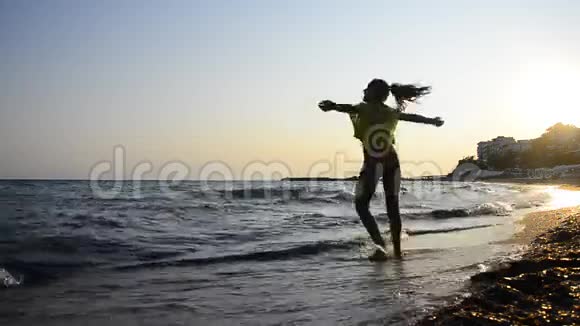 HD年轻女孩在日落时在海滩上旋转视频的预览图