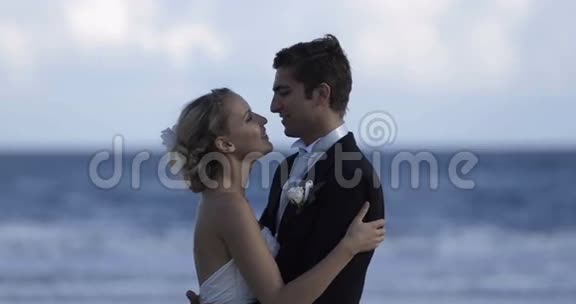 可爱的新婚夫妇拥抱在海滩上视频的预览图