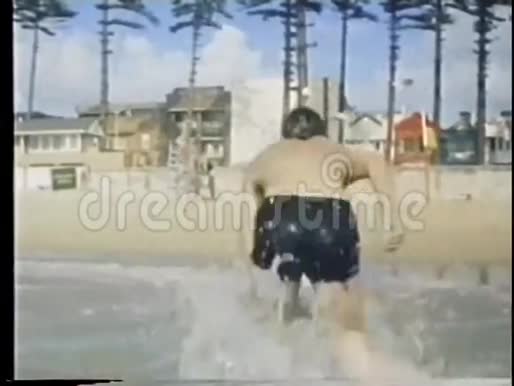 人从水中出来走到海滩的后景视频的预览图