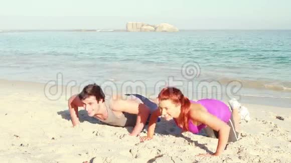 微笑的情侣在海滩做俯卧撑视频的预览图