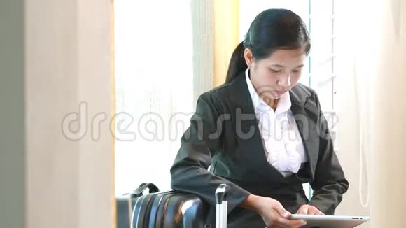 商务女性等待旅行和使用平板电脑视频的预览图