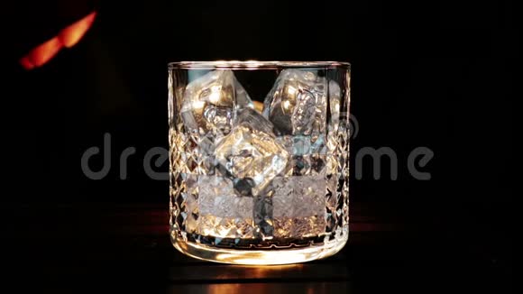 酒吧老板把威士忌倒在杯子里木桌上放冰块黑黑的背景把重点放在冰块上威士忌可以放松视频的预览图