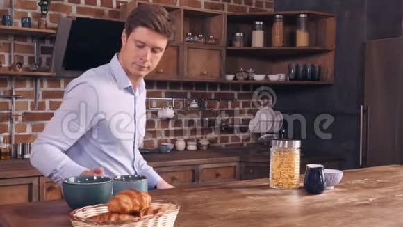 一个白人坐在桌旁把食物放在桌子上视频的预览图
