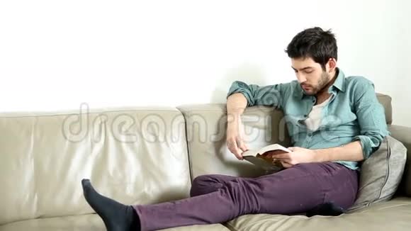 帅哥坐在舒适的沙发上看书视频的预览图
