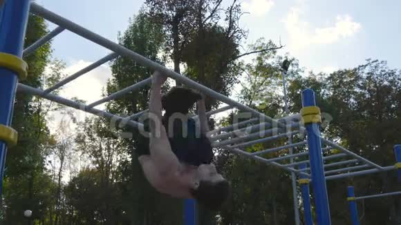 在城市公园的水平杆上做体操的运动员男运动员在比赛期间进行力量练习视频的预览图