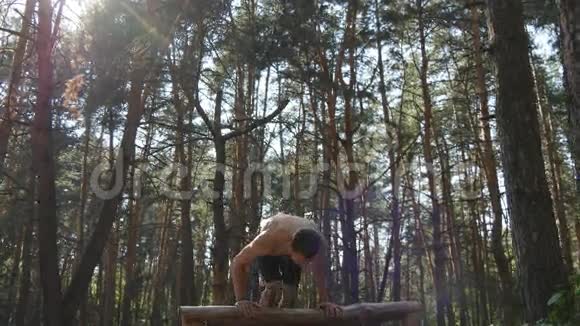 强壮的肌肉男在森林里做倒立肌肉男健身男在木头上做特技运动员视频的预览图