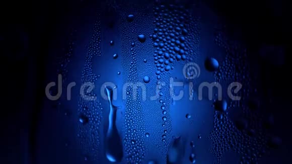 一滴水在一个玻璃特写宏观与闪闪发光的波克在蓝色模糊的背景抽象滴水雨滴视频的预览图